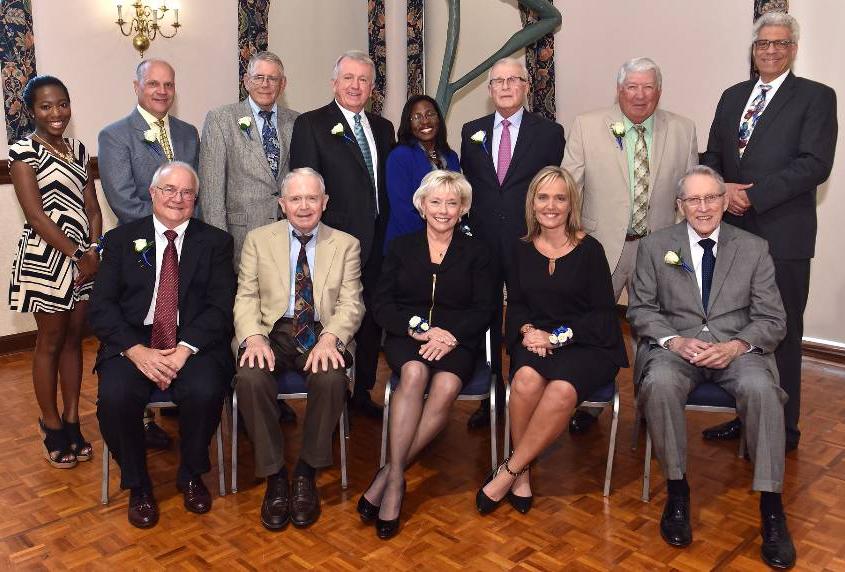 A group of men and women pose for a photo inside.